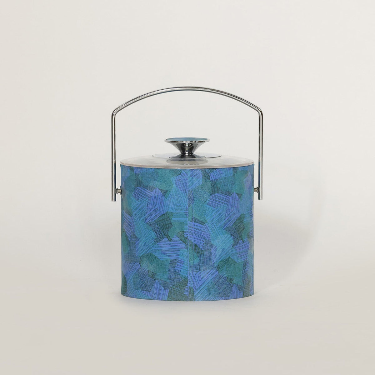 The Euro Trash Annie Mid Century Blue Lucite Ice Bucket features a cylindrical shape, abstract blue and teal pattern, shiny metal lid, and curved handle, adding a pop of color to modern decor against a white background.