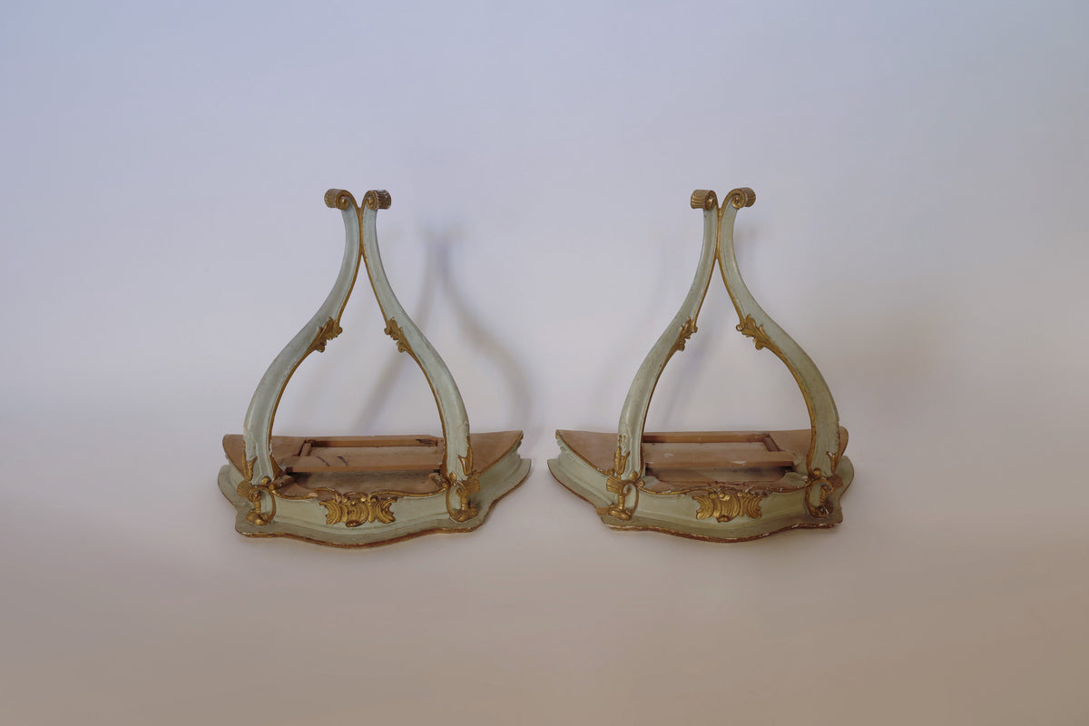 Displayed side by side against a plain background, this Pair Of Vintage Giltwood Wall Corbels by Euro Trash Annie features ornate curved frames, gold accents, and a pale green finish with visible wear—striking examples of antique architectural decor.