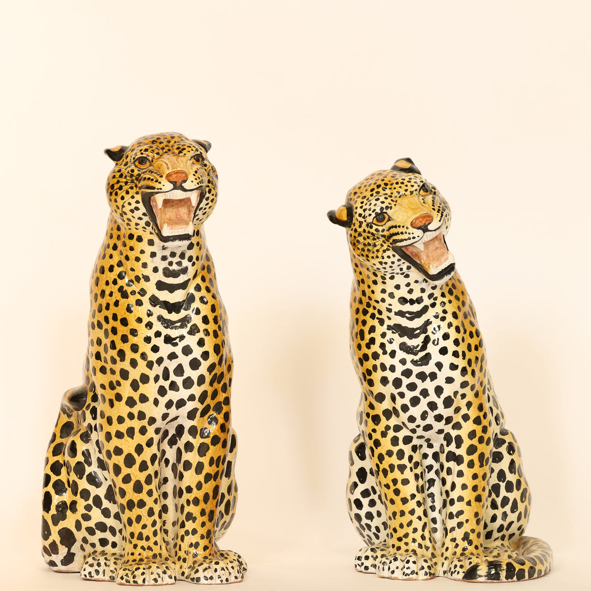 Two ceramic leopard figurines on a beige background