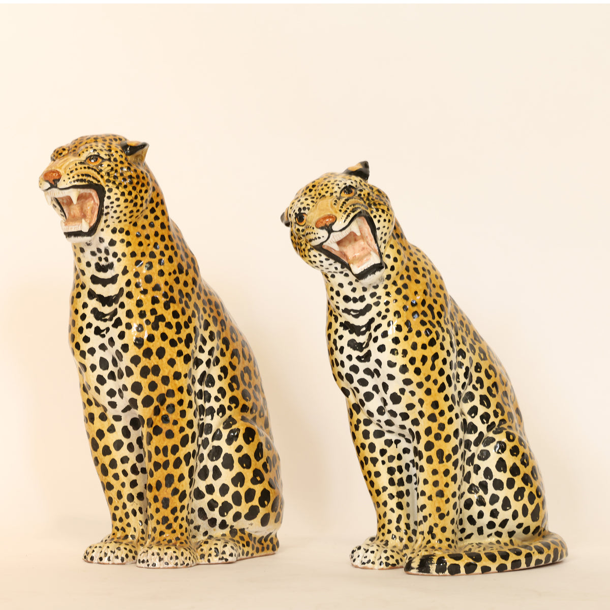 Two ceramic leopard figurines on a beige background