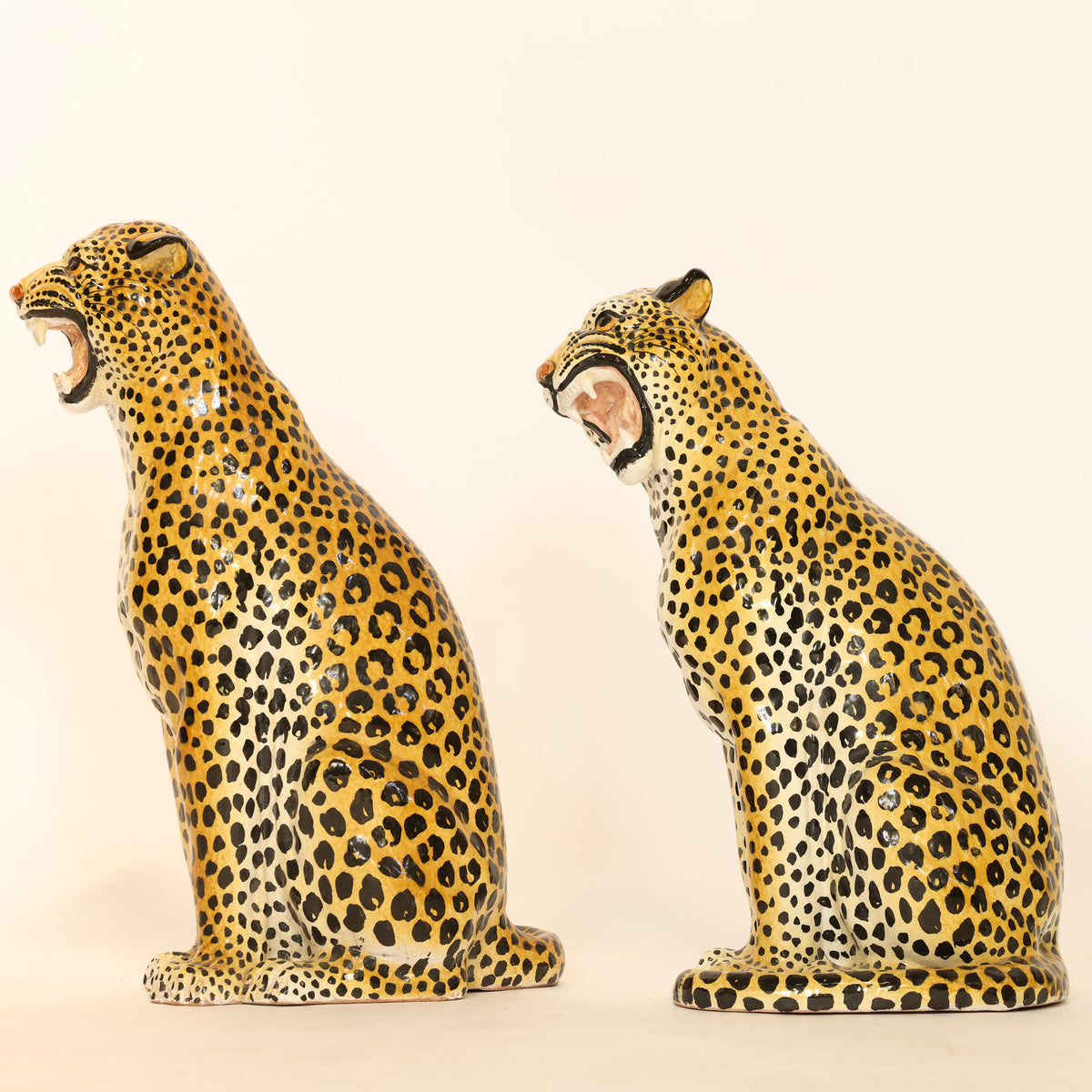 Two ceramic leopard figurines on a beige background