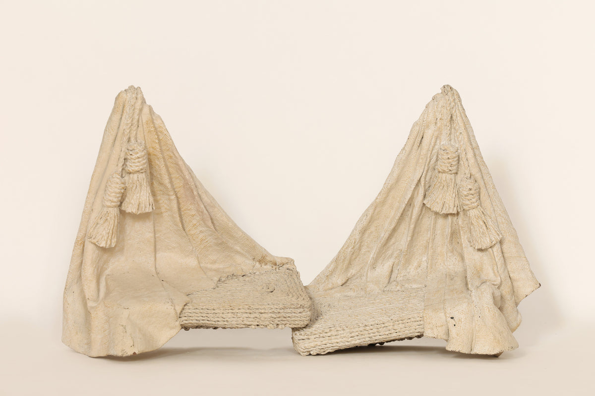 Sculptural pair of wall pieces on a beige background
