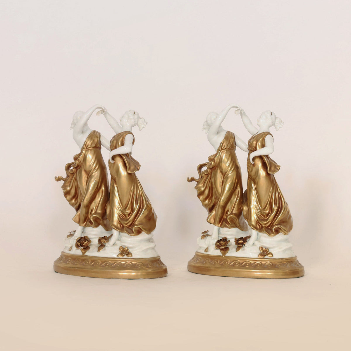 From Euro Trash Annie, the Pair of Gilt & Porcelain Dancing Figures features two identical women in gold dresses adorned with refined gilt accents and floral details, each standing on ornate bases. Facing each other against a simple, light background, these elegant figurines add a sophisticated touch to any refined setting.