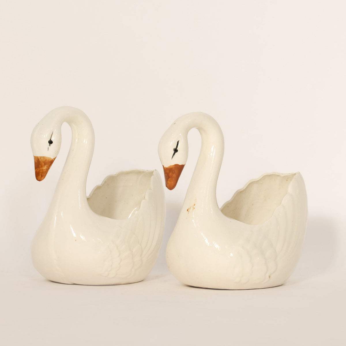 Two white swan-shaped ceramic pots on a light gray background