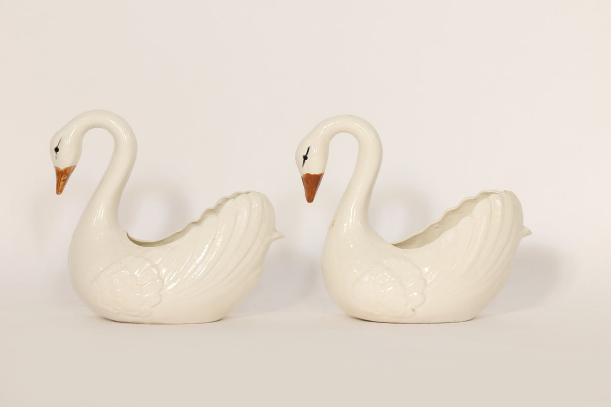 Two white ceramic swan-shaped ceramics on a light gray background