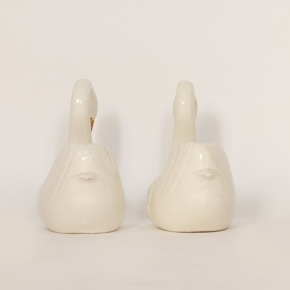 Two white ceramic swans on a light beige background