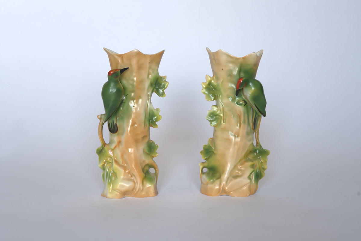 The Euro Trash Pair of Vintage Ceramic Hand-Painted Bird Vases features tree trunk shapes with green leaves and red-accented birds, all set against a plain white background for a charming cottage look.