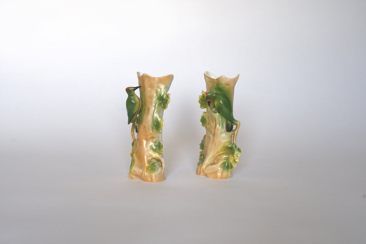 The Pair of Vintage Ceramic Hand-Painted Bird Vases by Euro Trash features tree trunk shapes with green leaves and perched birds, displayed side by side on a plain light background for a charming cottage look.