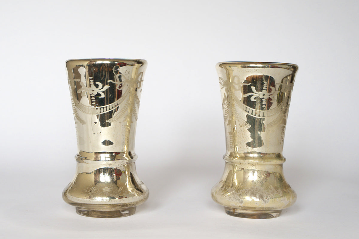 The Pair of Vintage Etched Mercury Glass Vases by Euro Trash features flared tops, engraved patterns, a silvered reflective finish, and rounded bases, showcased against a plain white background.