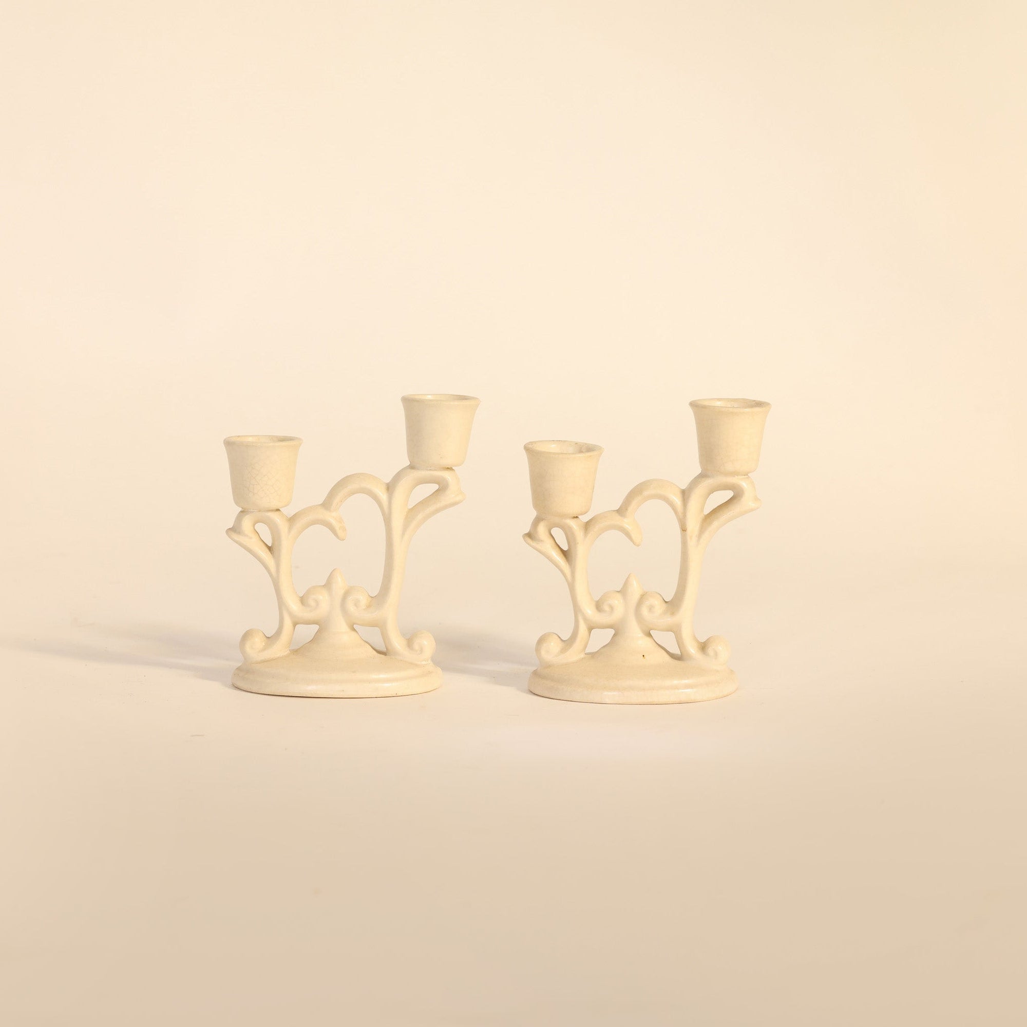 Two cream-colored candle holders on a beige background