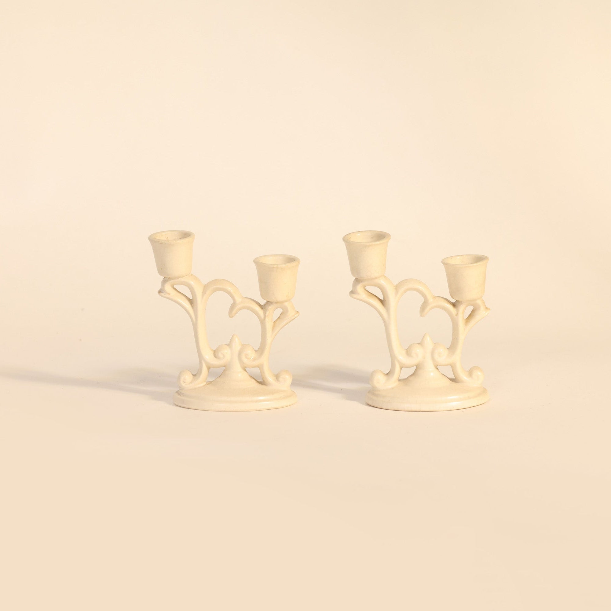 Two cream-colored candle holders on a beige background