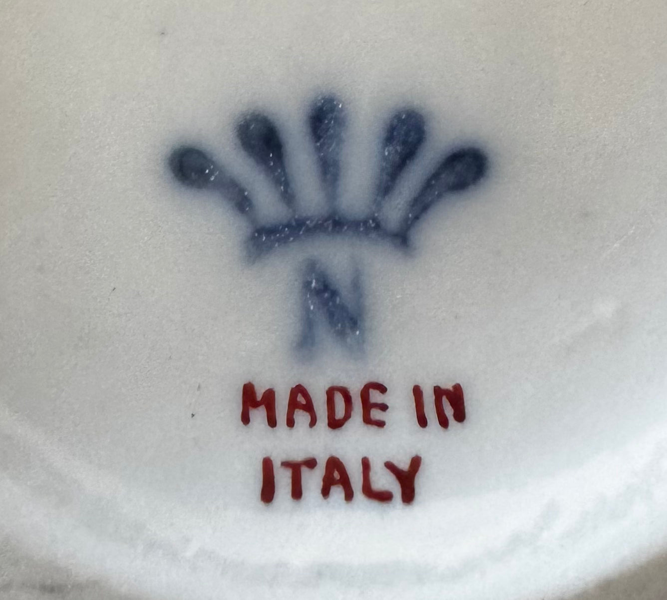 Euro Trash Annie Set of Four Gilt & Porcelain Figurines with a blue crown-like mark and an "N" above red "MADE IN ITALY" text on white ceramic, often featuring gilt detailing.