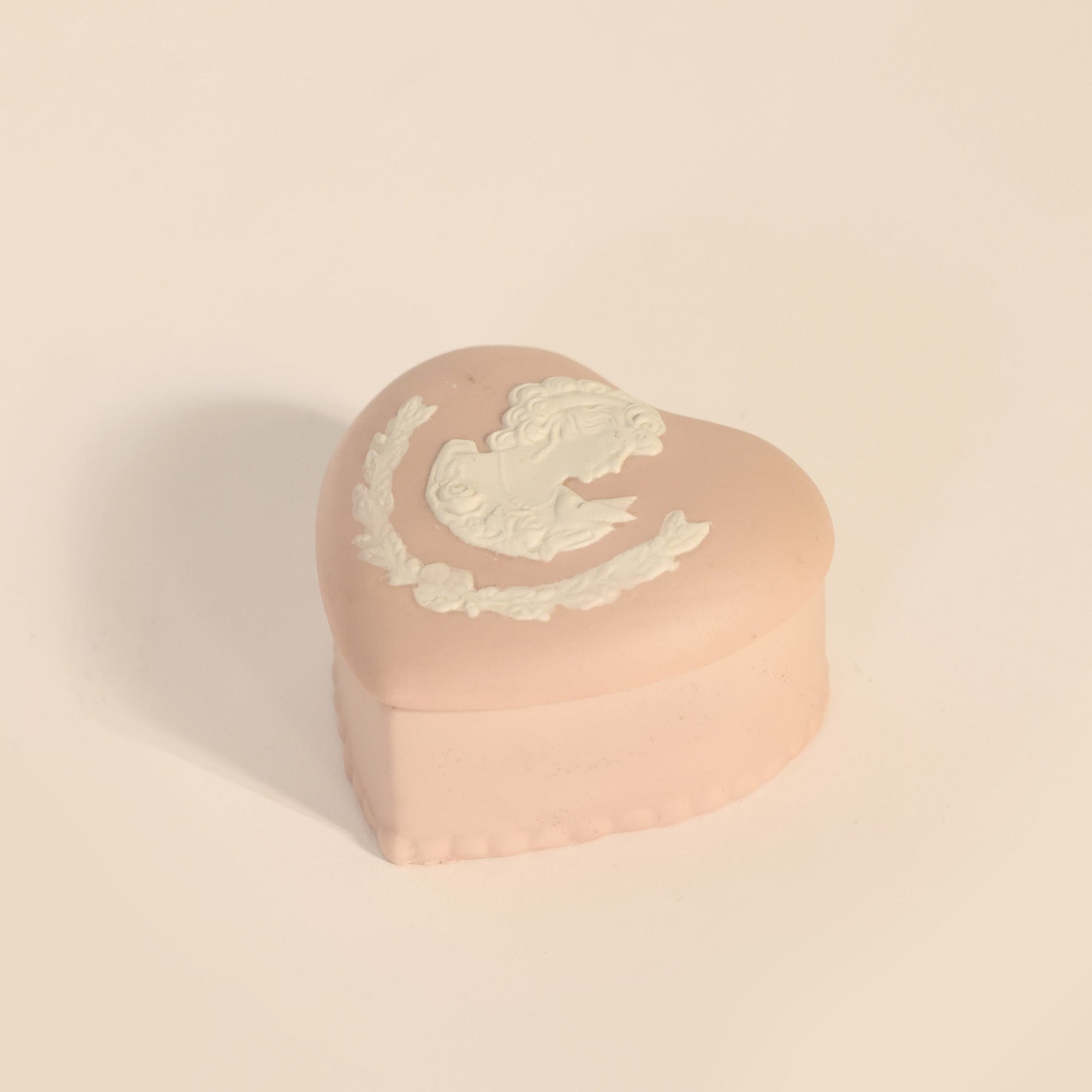 The Vintage Jasperware Style Heart Trinket Box by Euro Trash Annie is a small, pink box with classical white relief, a woman's cameo, and laurel accents on the lid, shown against a plain light background.