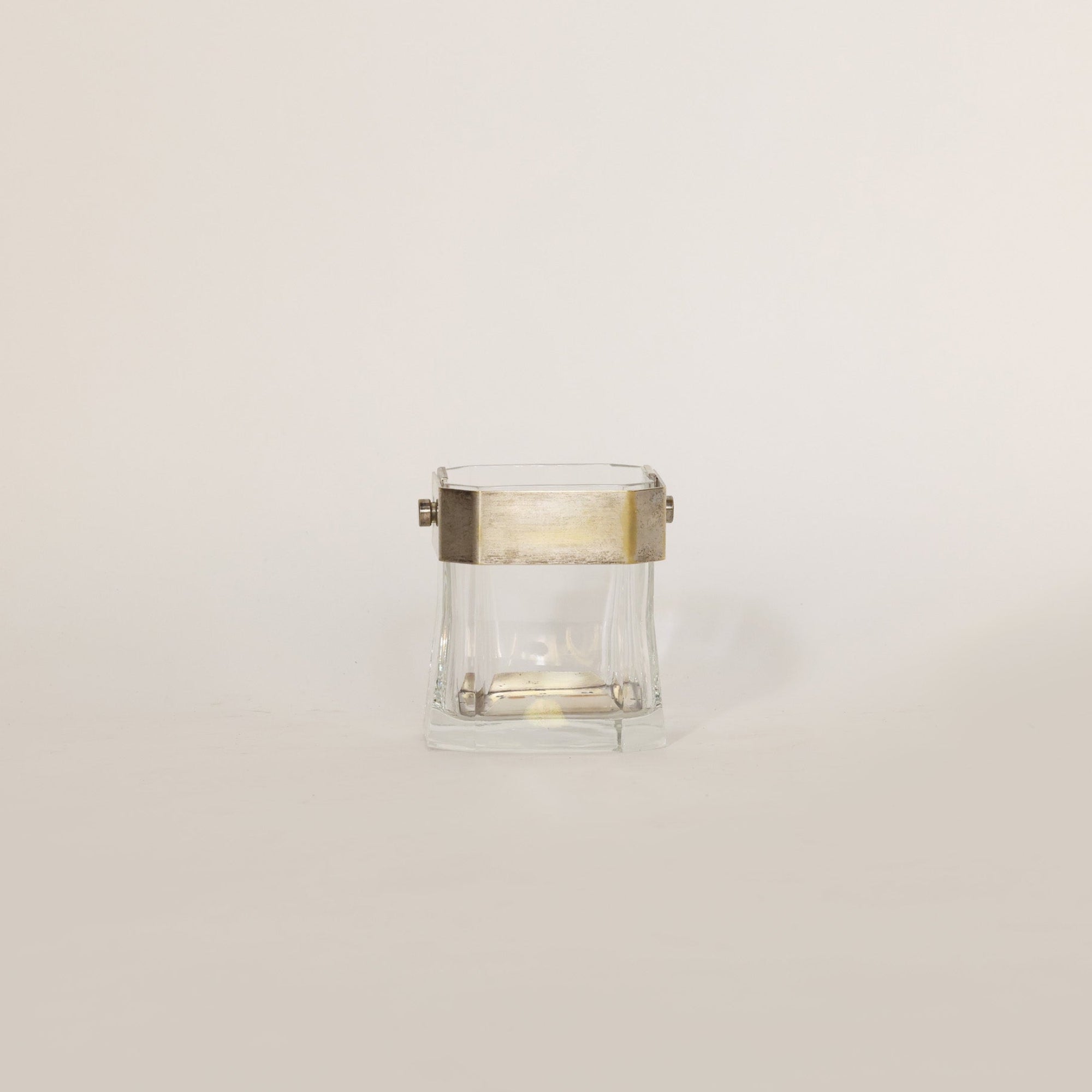Vintage glass vessel composed of crystal and brass on beige background 