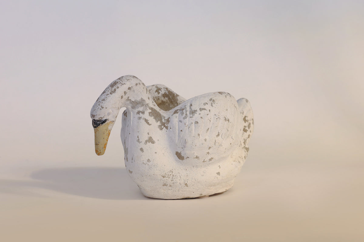The Vintage Distressed Swan Planter by Euro Trash Annie is a weathered, white ceramic planter shaped like a swan, featuring chipped paint and worn details for a distressed finish. Set against a plain, light background, this sculptural piece adds character and charm to any space.