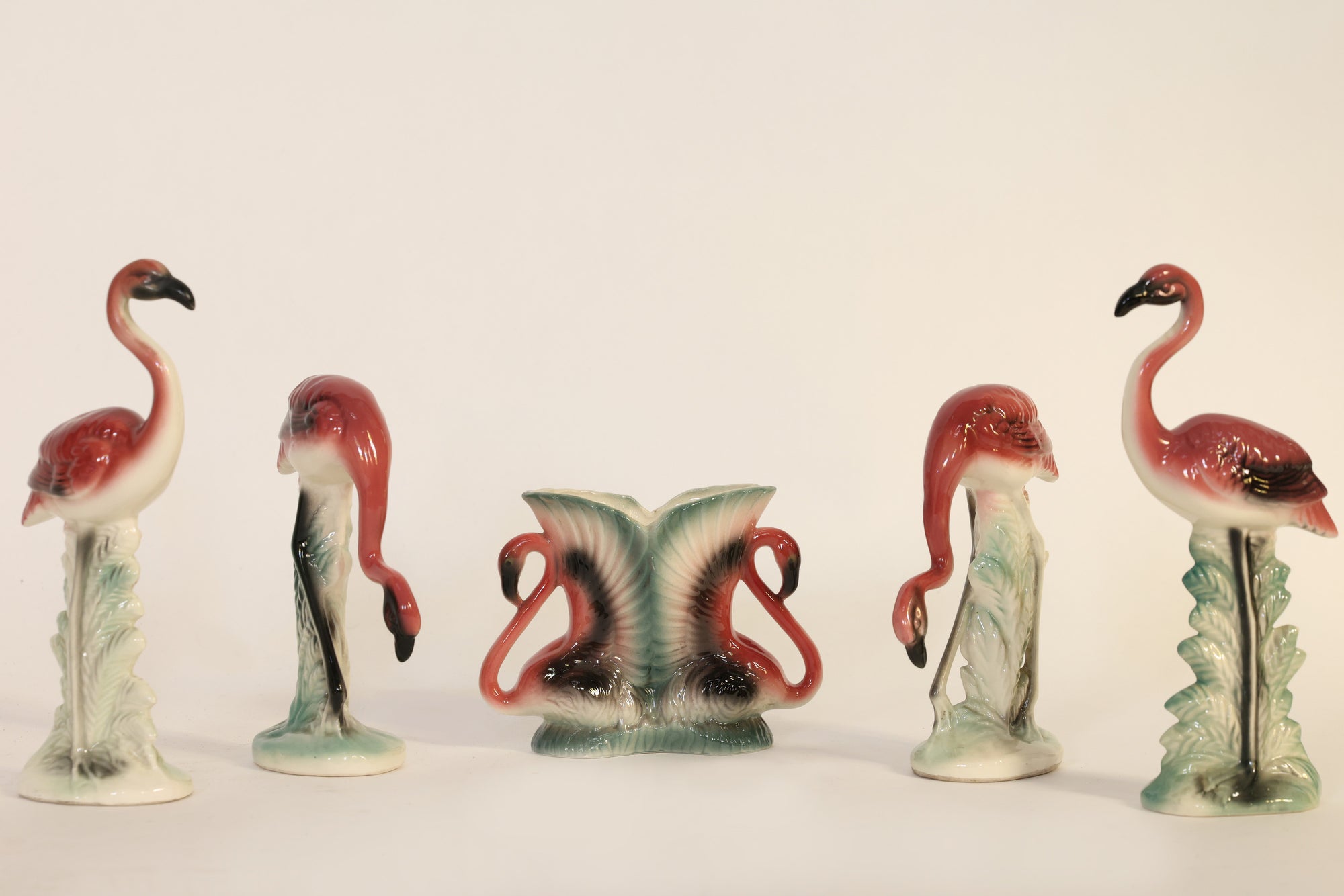 Set of ceramic flamingo figurines on a white background