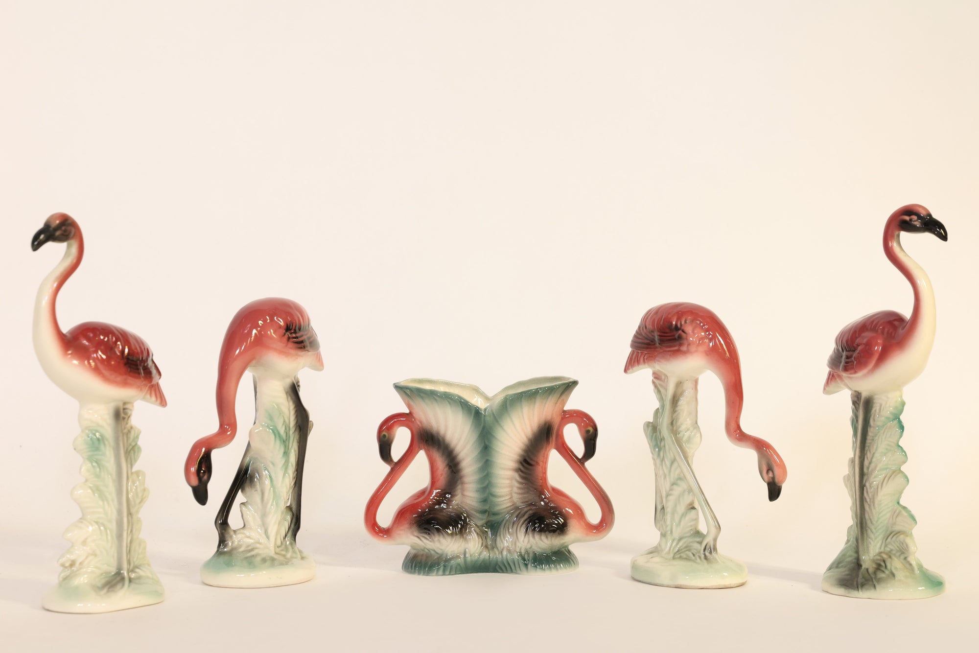 Set of ceramic flamingo figurines on a plain background