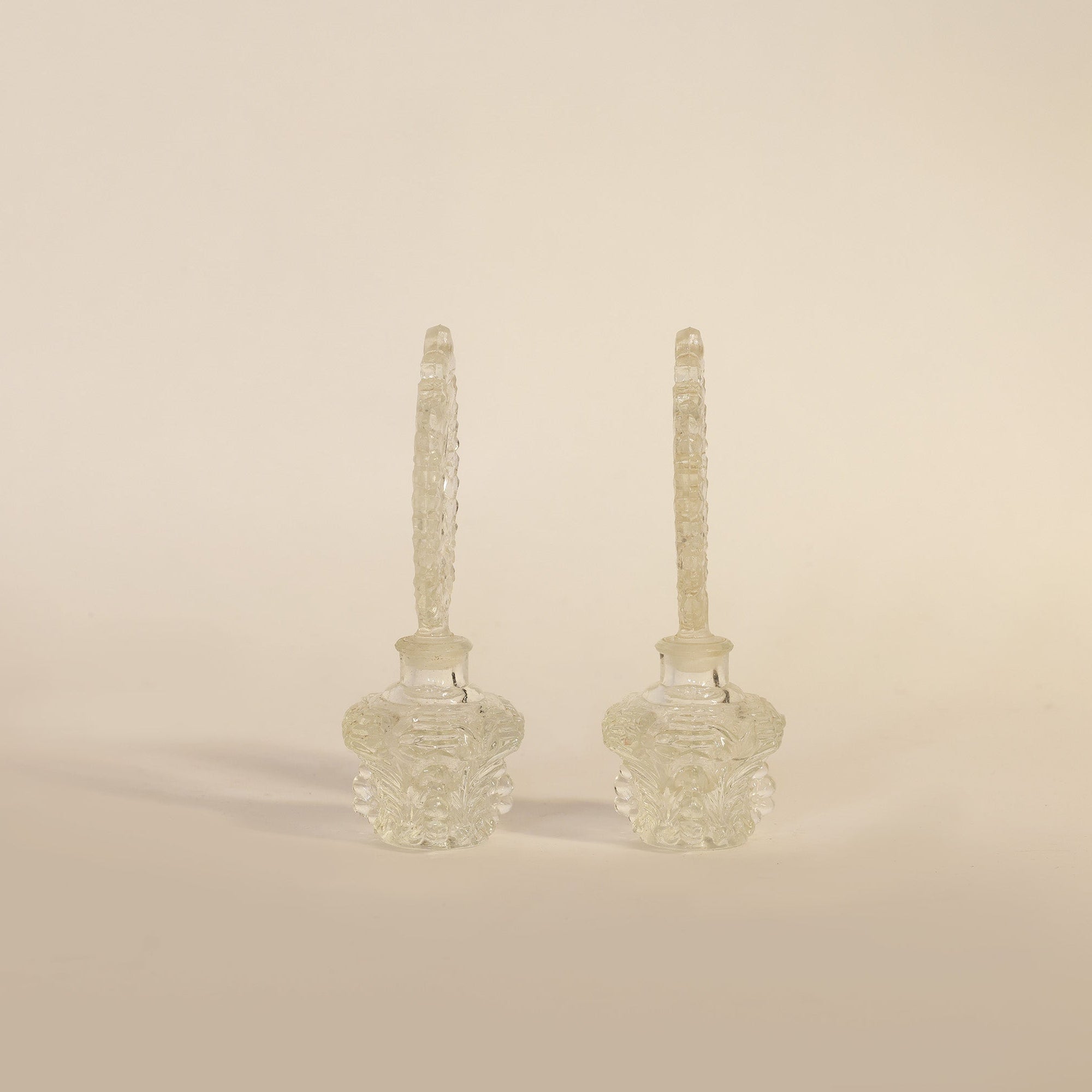 pair of vintage pressed glass perfume bottles on beige background