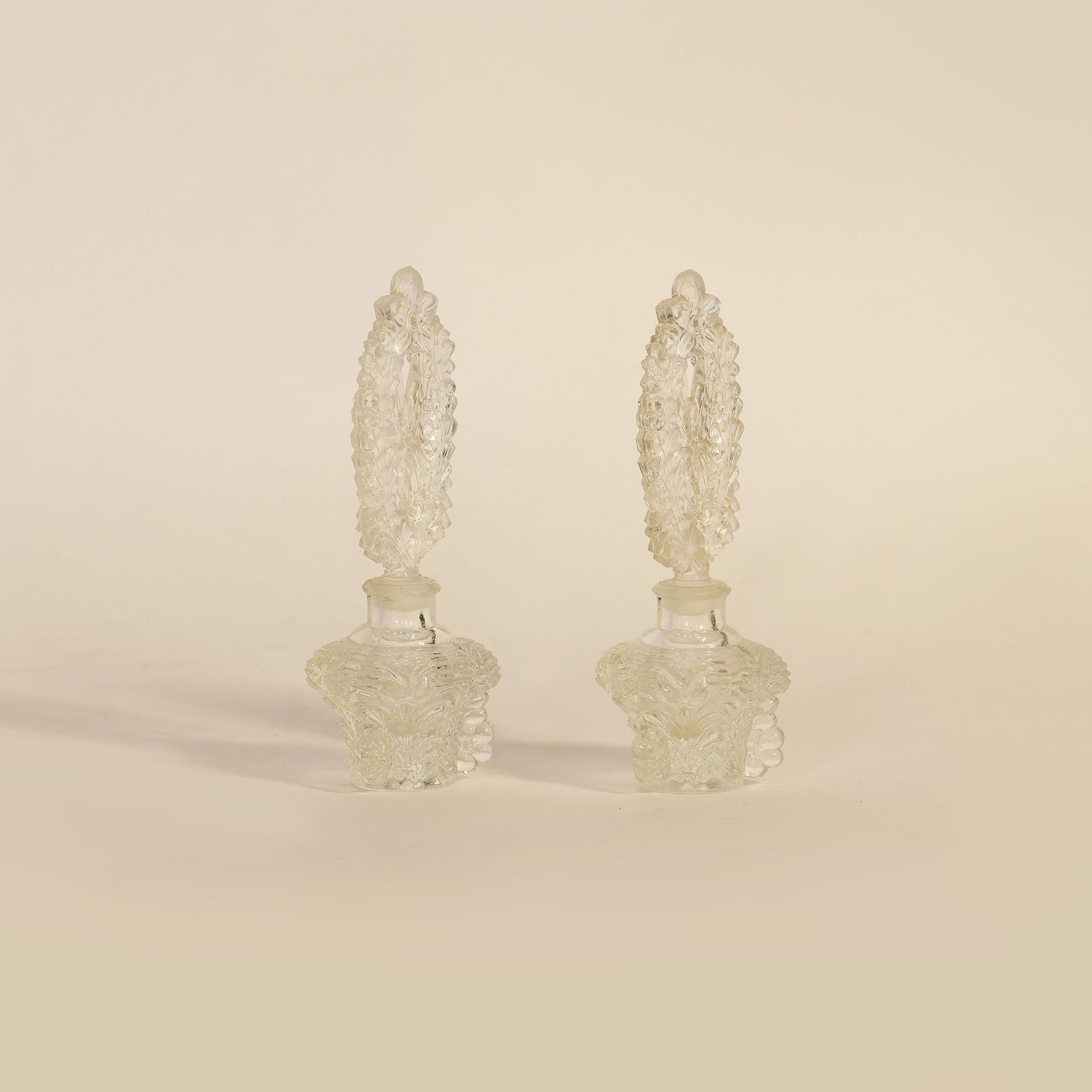 pair of vintage pressed glass perfume bottles on beige background