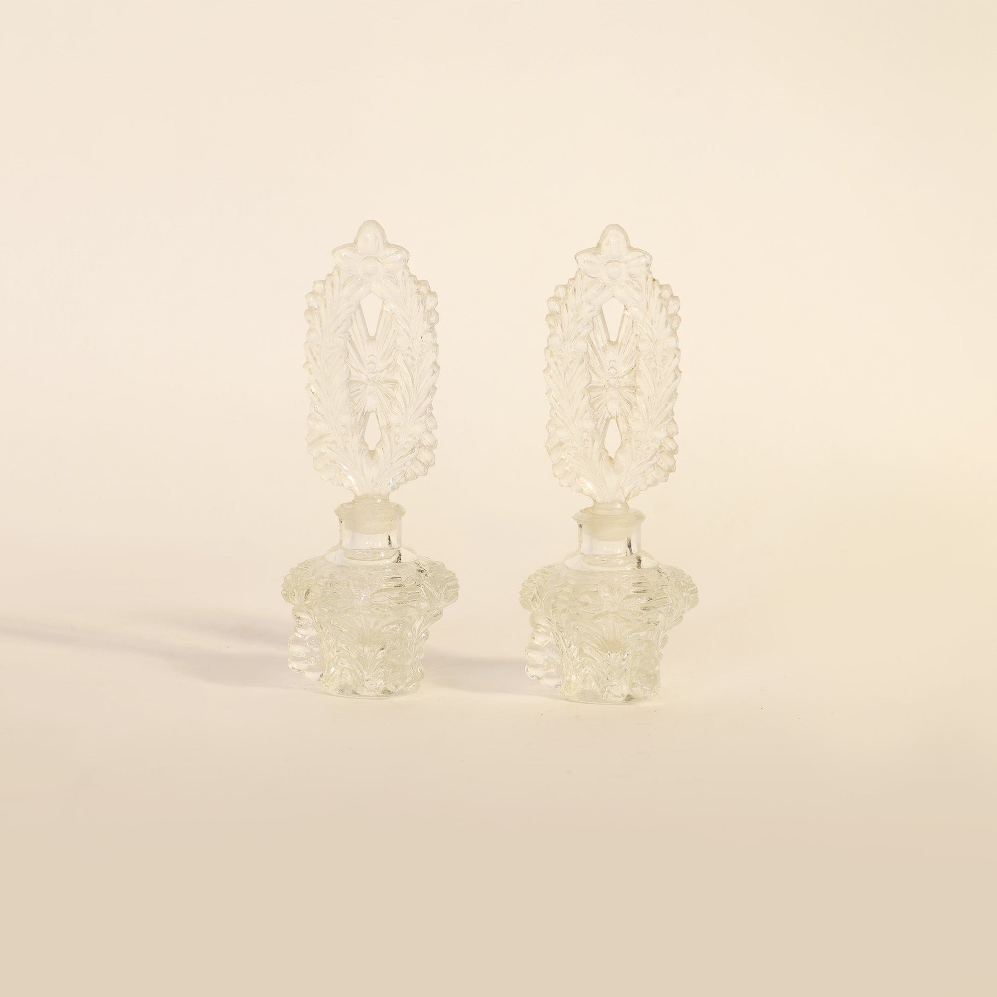 pair of vintage pressed glass perfume bottles on beige background