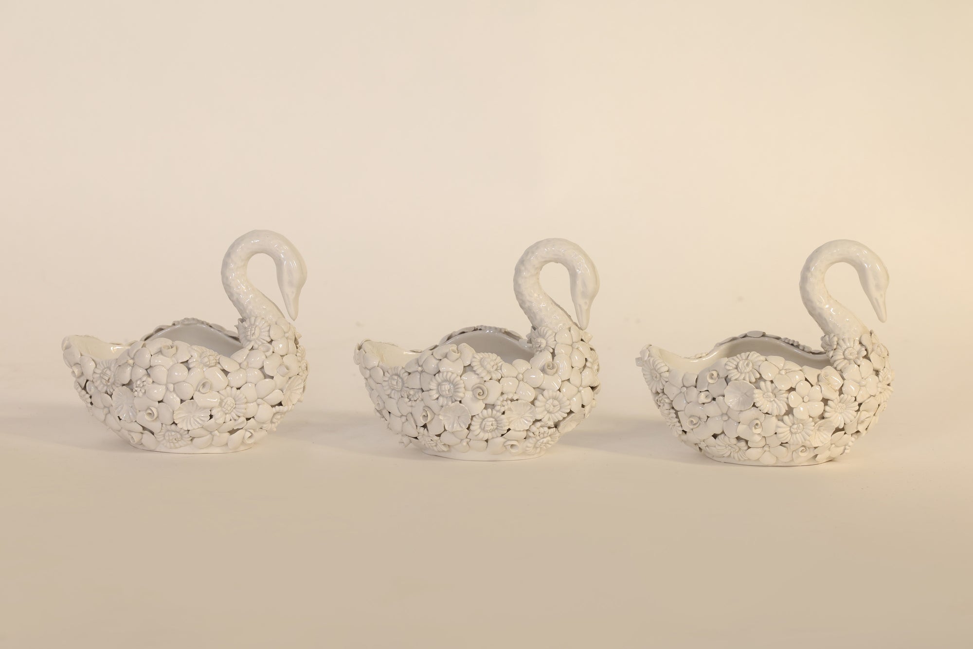 Three decorative swan-shaped figurines on a beige background