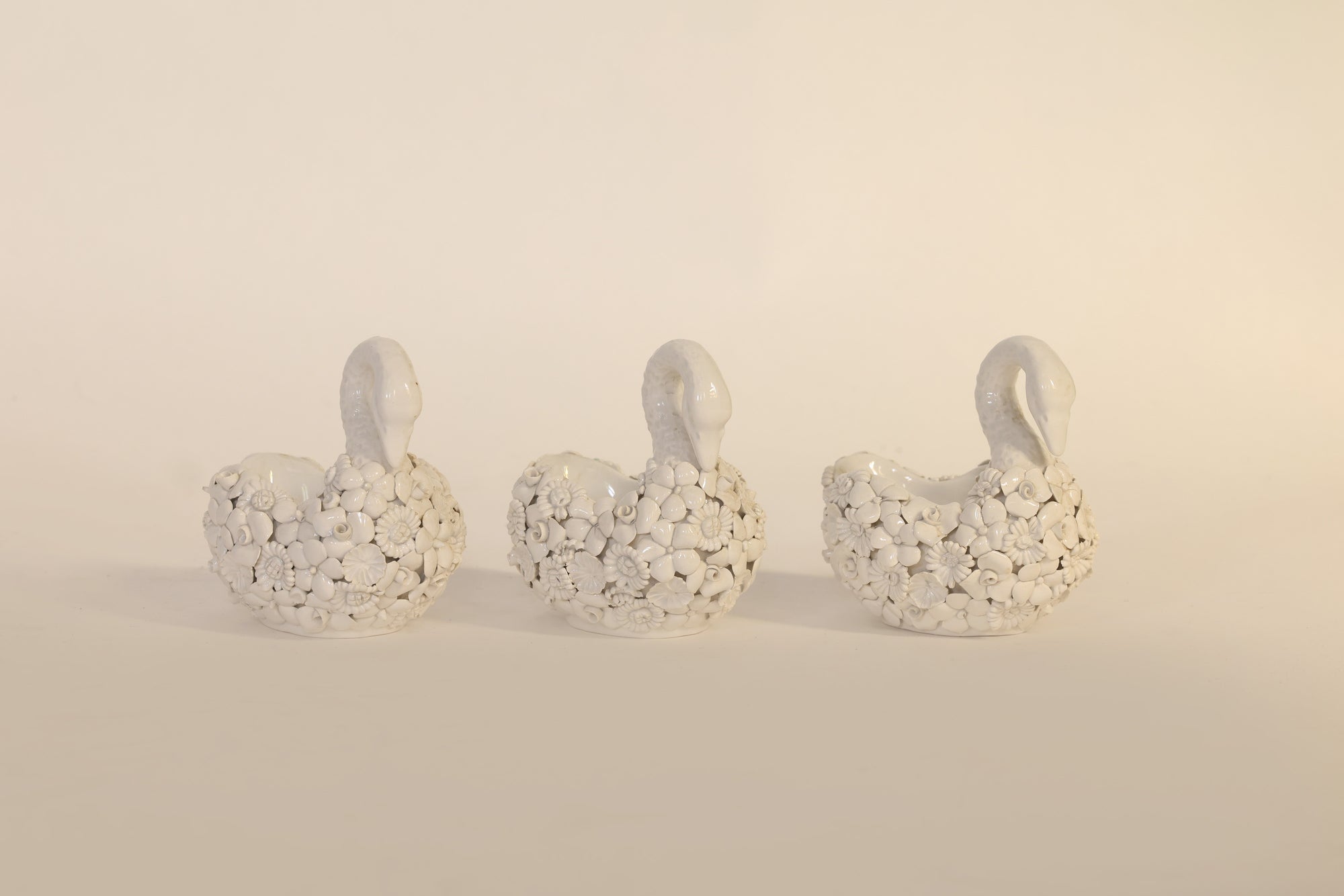 Three decorative swan figures on a beige background