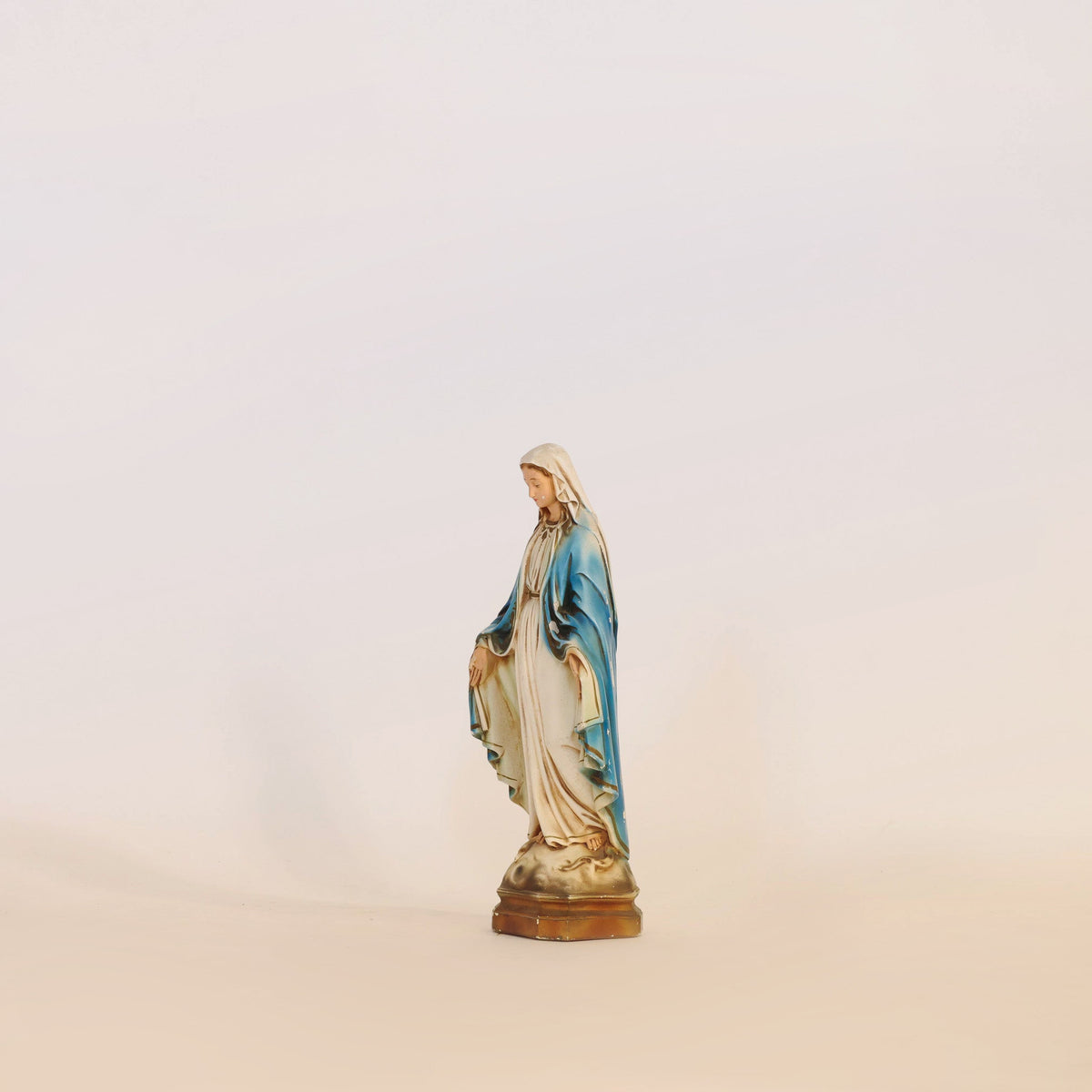The Euro Trash Annie Vintage Virgin Mary Statue, elegantly adorned in blue and white, stands serenely on a light surface with a subtle background—an ideal addition to spiritual home decor.