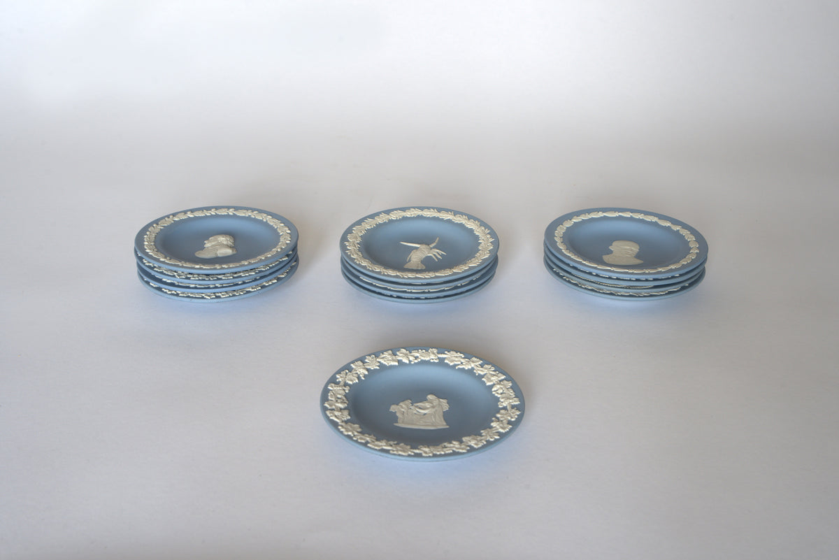 Five stacks of Euro Trash Vintage Blue Jasperware Style Relief Plates with white figures and ornate borders are displayed on a white background. One stack is separated in front, ideal for a vintage wall display plate set.