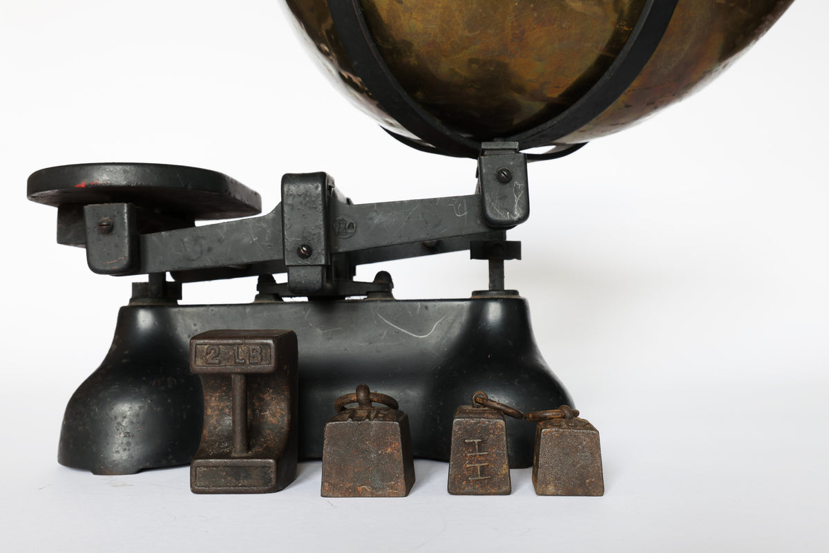 The Euro Trash Annie Vintage Brass Balance Scale features a black frame, brass pan, and assorted metal weights—crafted for striking decorative appeal against a plain white background.