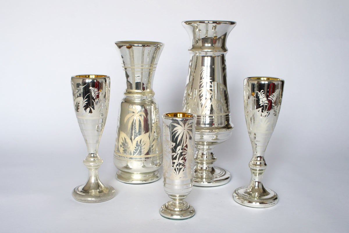 The Euro Trash Vintage Etched Mercury Glass Vessel Set includes five assorted vases and goblets with silvered finish, gold-rimmed interiors, and etched botanical designs, arranged on a plain white background.