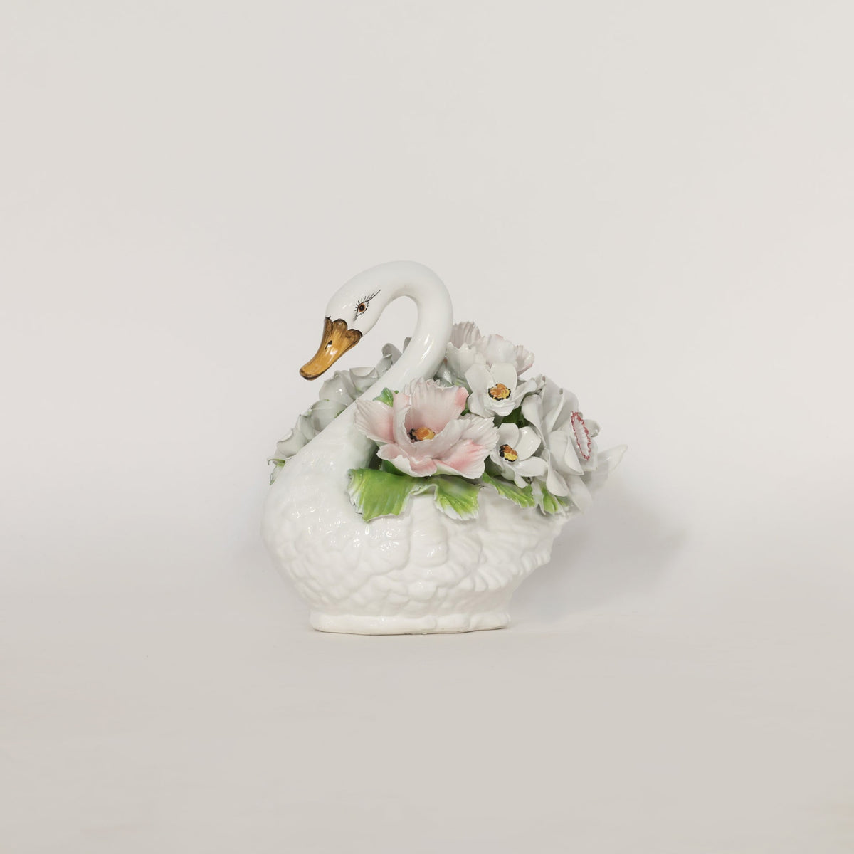 Decorative ceramic swan with flowers on a light gray background