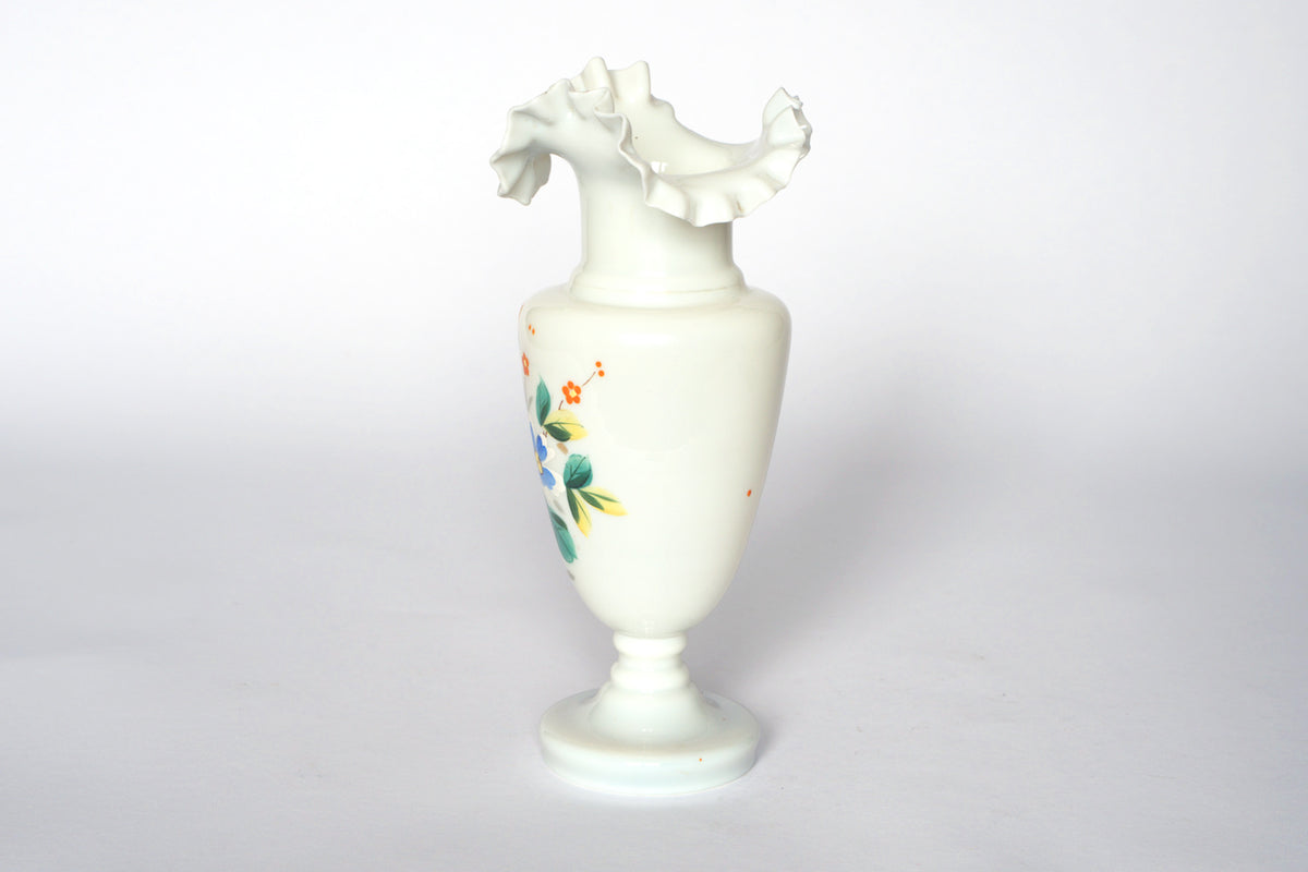 The Vintage Hand-Painted Milk Glass Vase by Euro Trash features a ruffled, flared rim, hand-painted floral design, and a round pedestal base, shown against a plain white background.