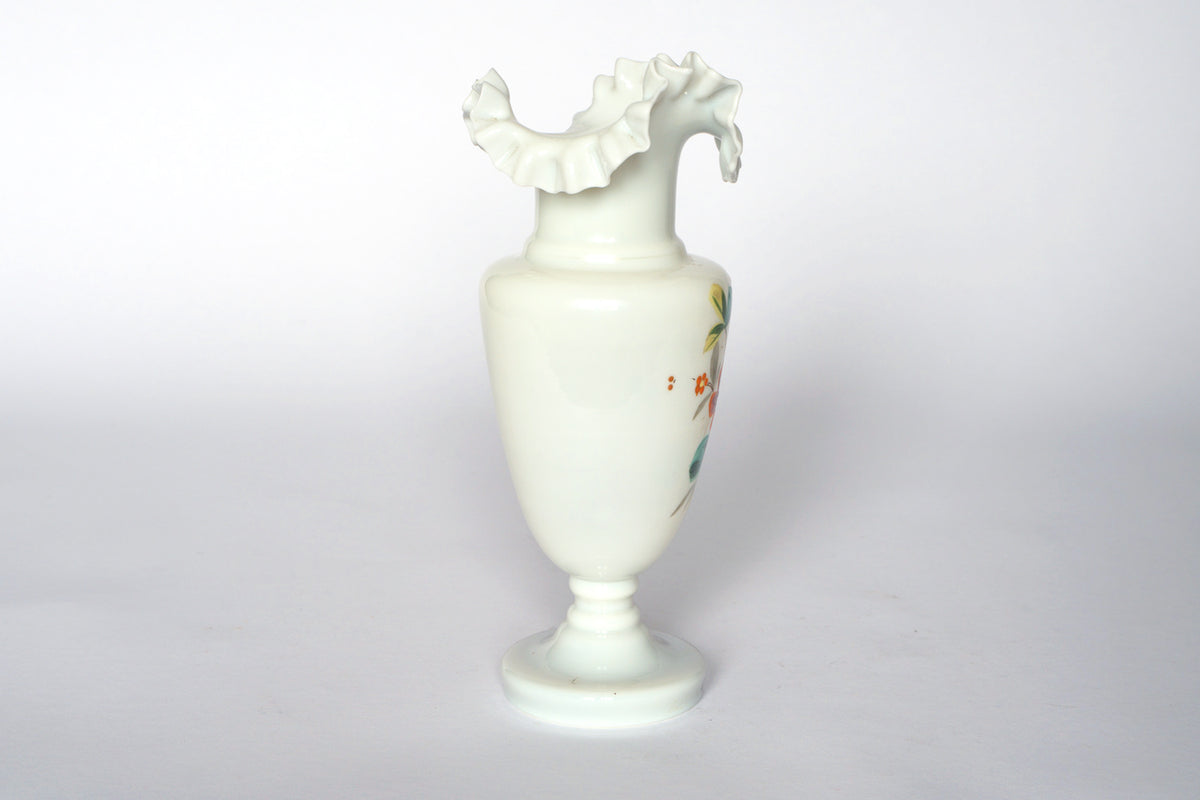 The Euro Trash Vintage Hand-Painted Milk Glass Vase features a narrow stem, wide body, ruffled rim, and one side adorned with floral designs. Displayed against a white background.