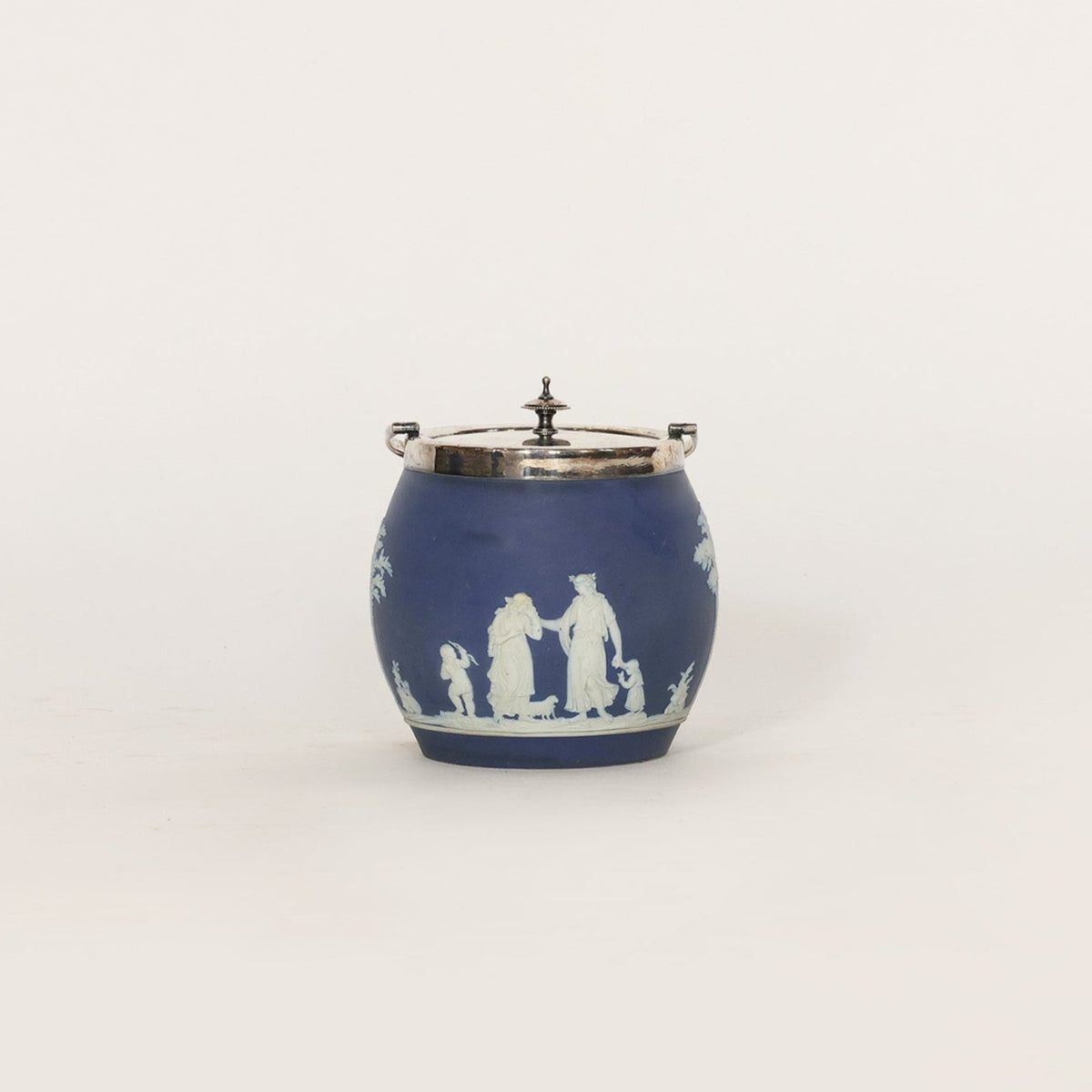 Blue ceramic jar with white decorative figures on a light gray background