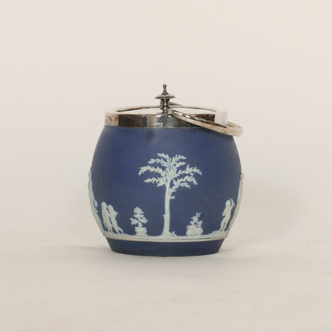 Blue ceramic jar with white decorative figures on a light gray background