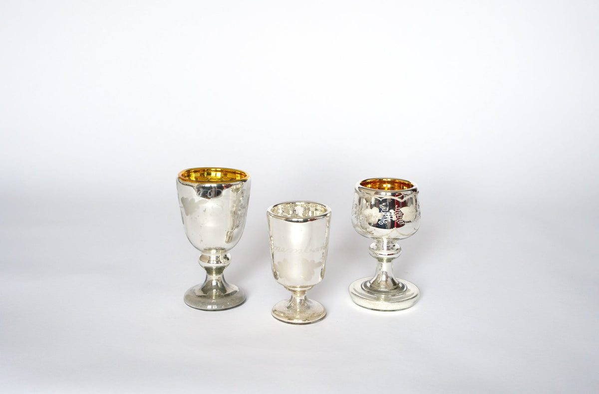The Euro Trash Vintage Mercury Glass Stemmed Cup Set features three etched cups of varying heights and shapes, each with a gold interior and subtle tarnish. Displayed side by side on white, they're a charming decorative accent.