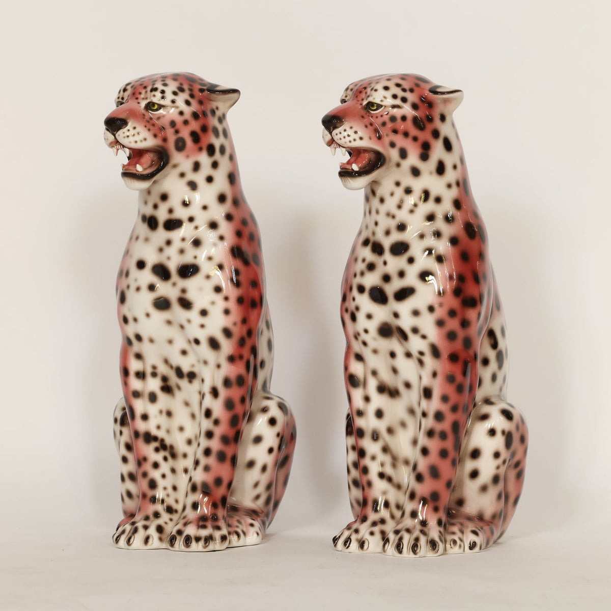 Two ceramic cheetah figurines on a plain background