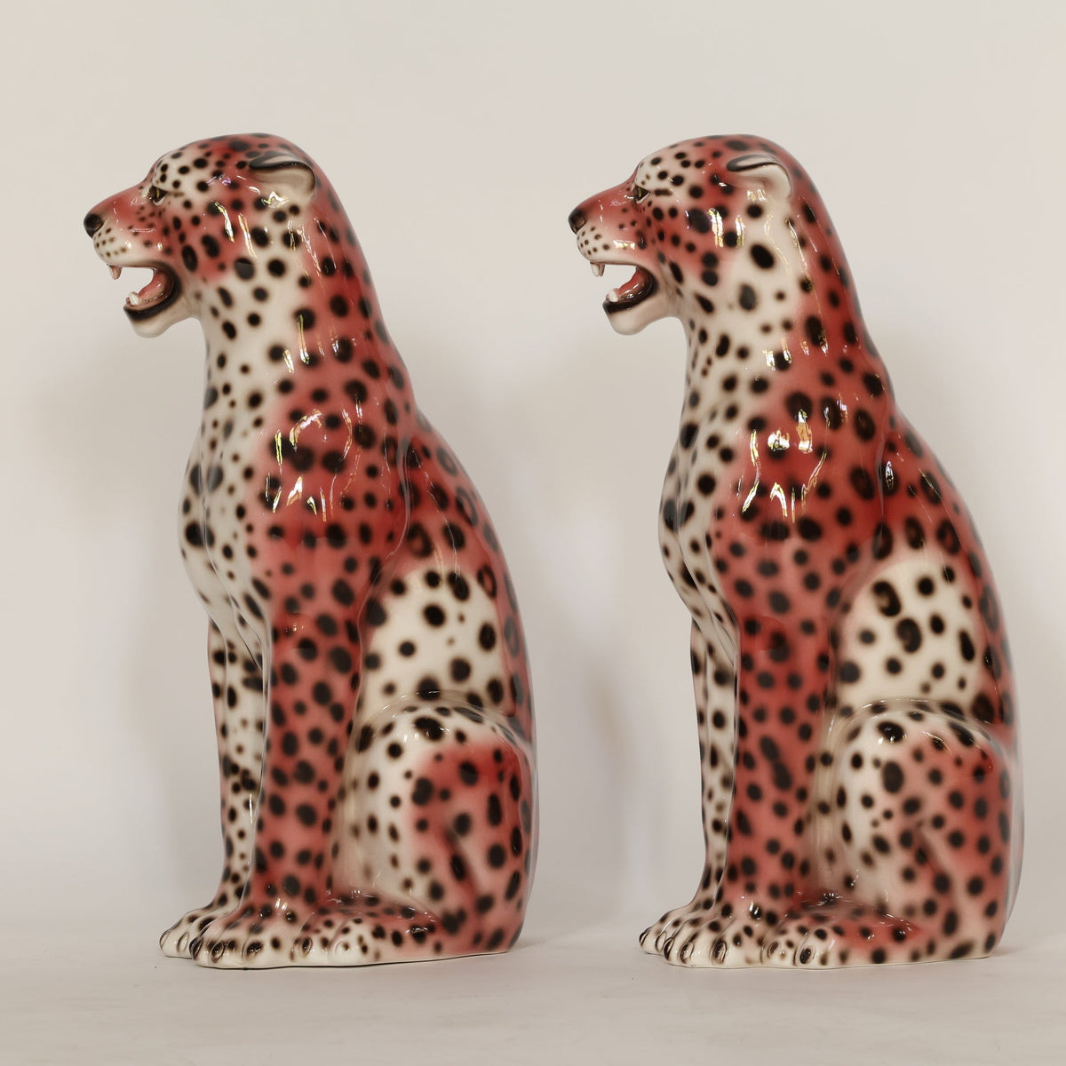 Two ceramic leopards on a plain background