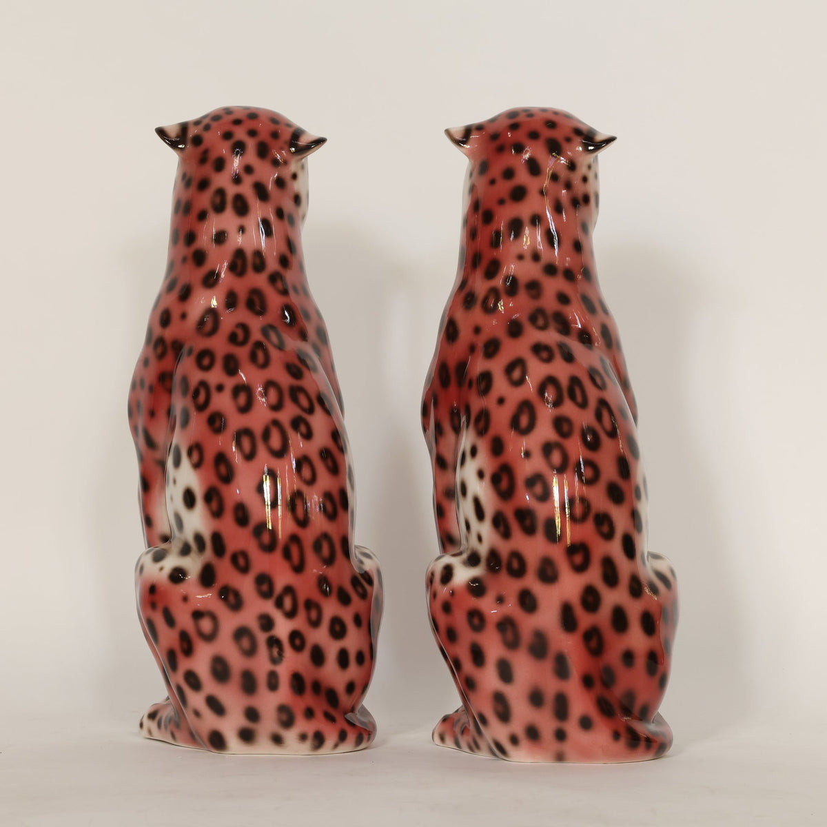 Two ceramic animal figurines with leopard print design on a plain background
