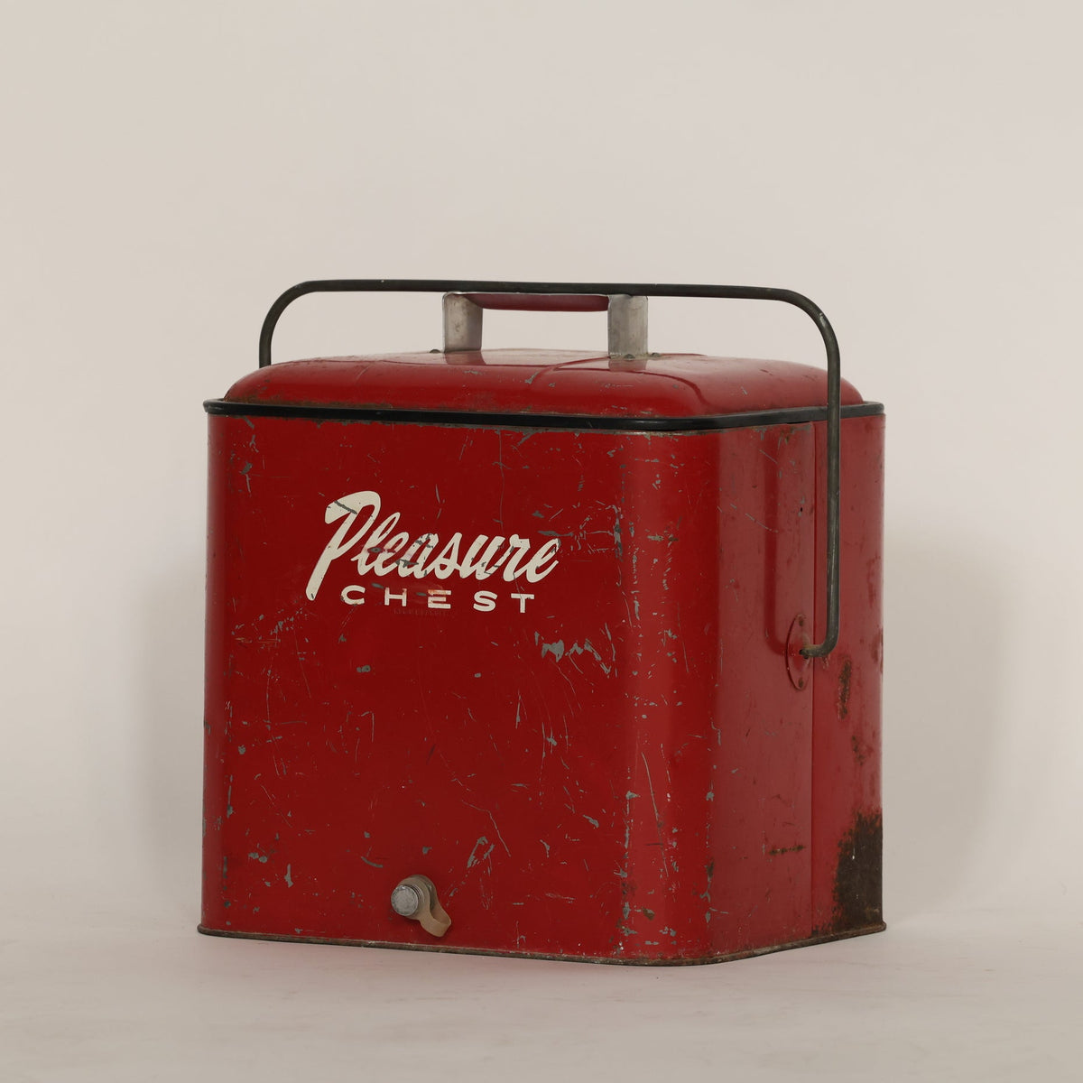 Vintage red metal box with 'Pleasure Chest' branding on a light gray background