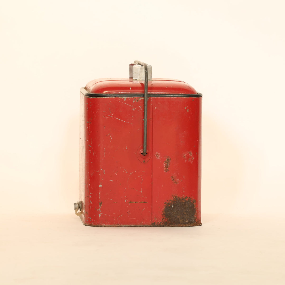 Vintage red metal box with brass handle on a beige background