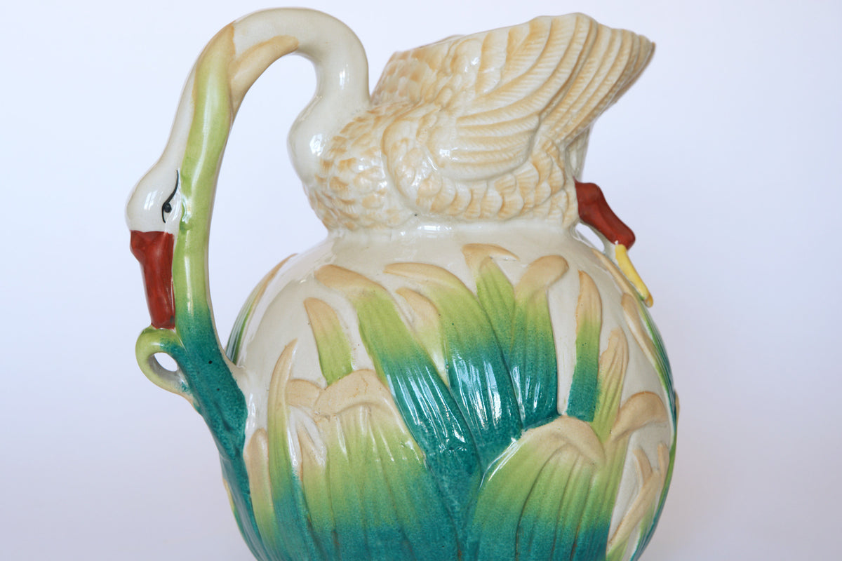 The Euro Trash Vintage Swan Motif Ceramic Pitcher with Cattail Design features a swan-shaped handle and detailed green, cream, and yellow reed and feather patterns, adding decorative charm to this hand-painted vintage piece.