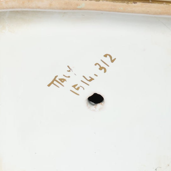 Close-up of a Vintage White & Gold Urn Vase with Draped Garland Detail by Euro Trash, showing handwritten ITALY 1514.312 in brown on its neoclassical ceramic surface and a small round black mark below the text.