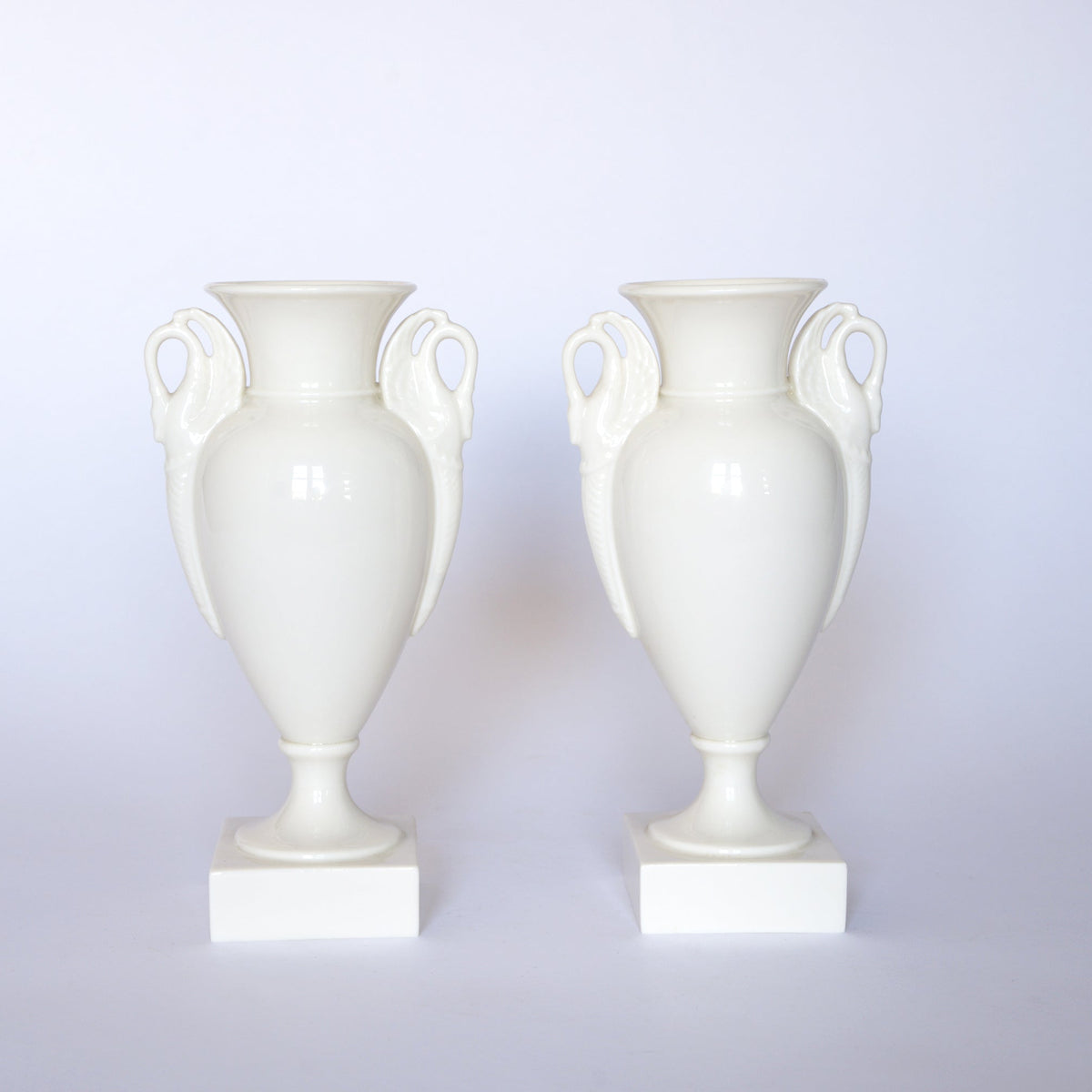 A pair of Euro Trash Vintage White Swan Handle Ceramic Urn Vases, each featuring elegant swan handles and a square base, are displayed against a plain white background.