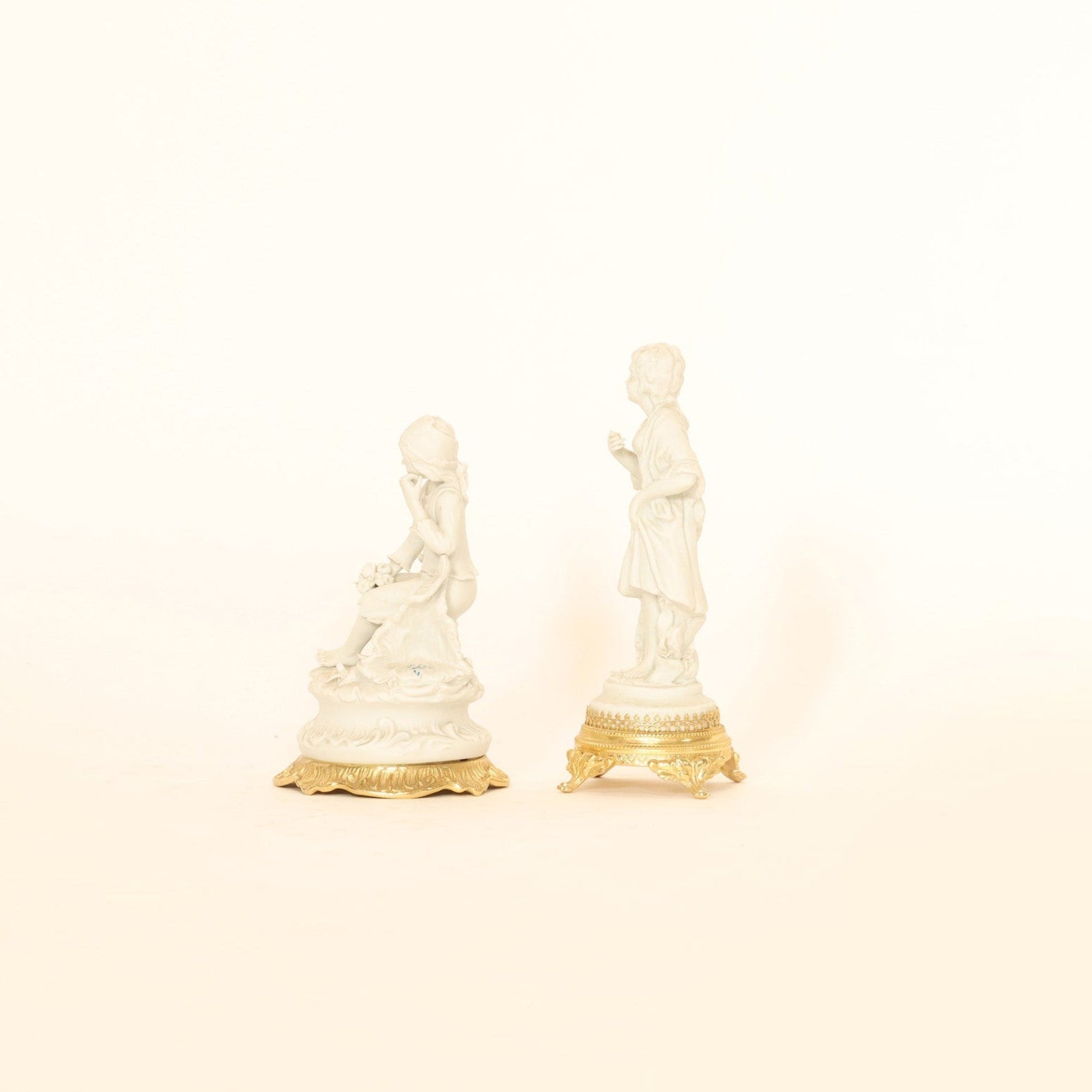 Two small decorative figurines on a beige background