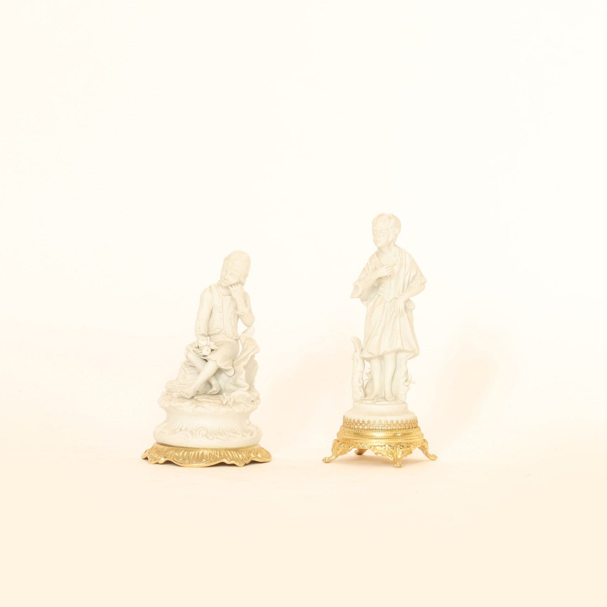 Two small figurines on a beige background