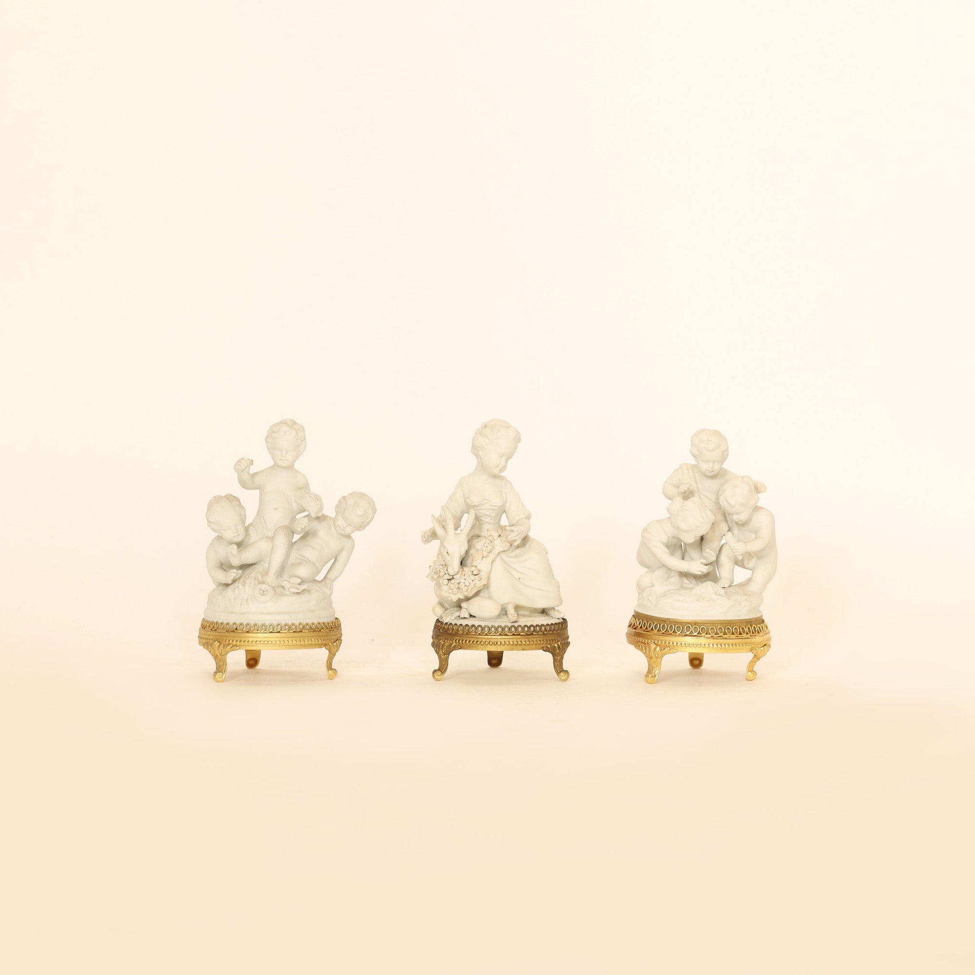 Three small decorative figurines on a beige background