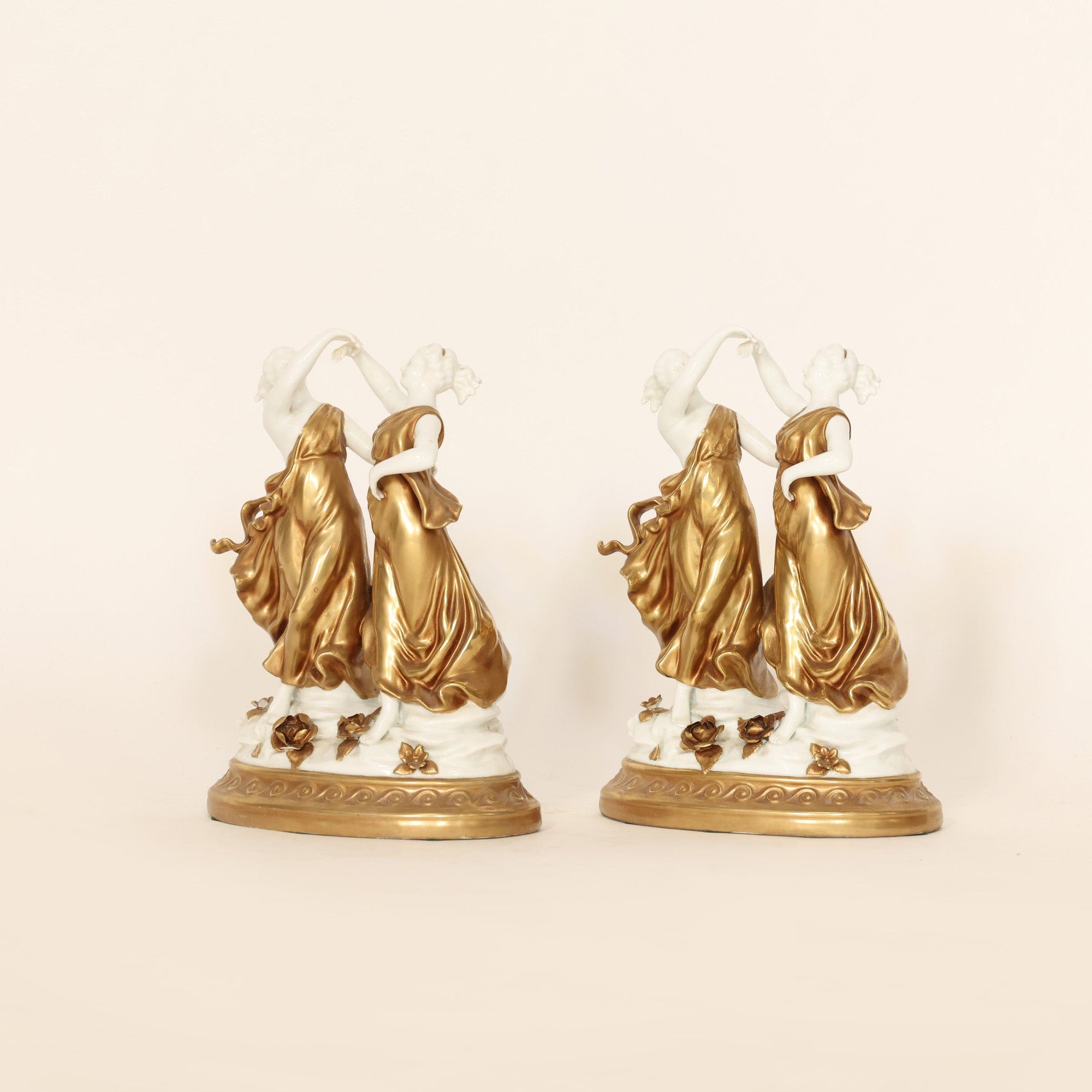 Two decorative figurines with gold accents on a beige background