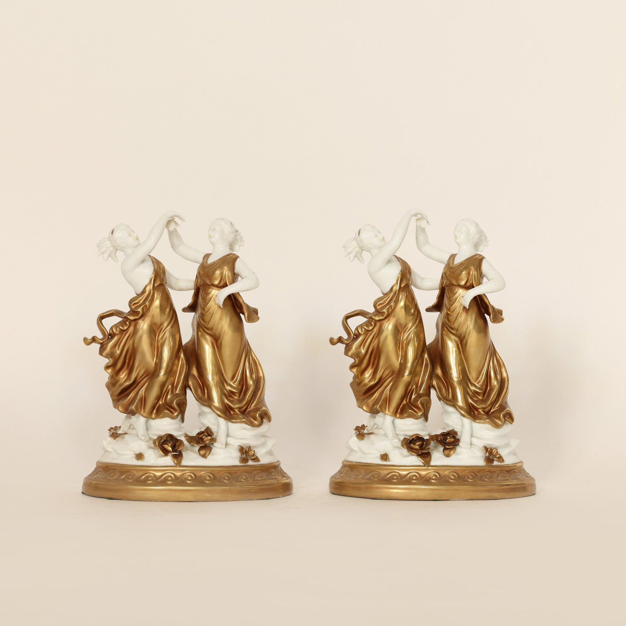 Two gold and white decorative statues on a beige background