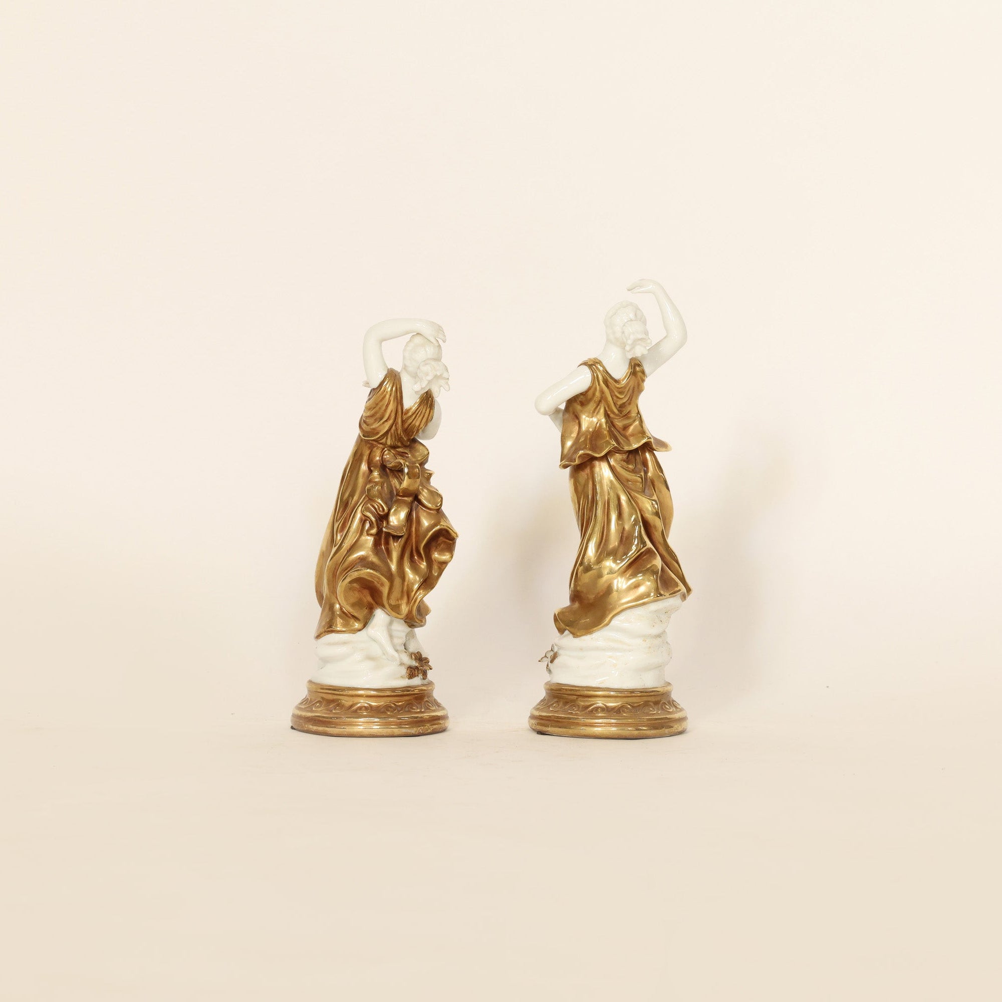 Two gold and white decorative figures on a beige background